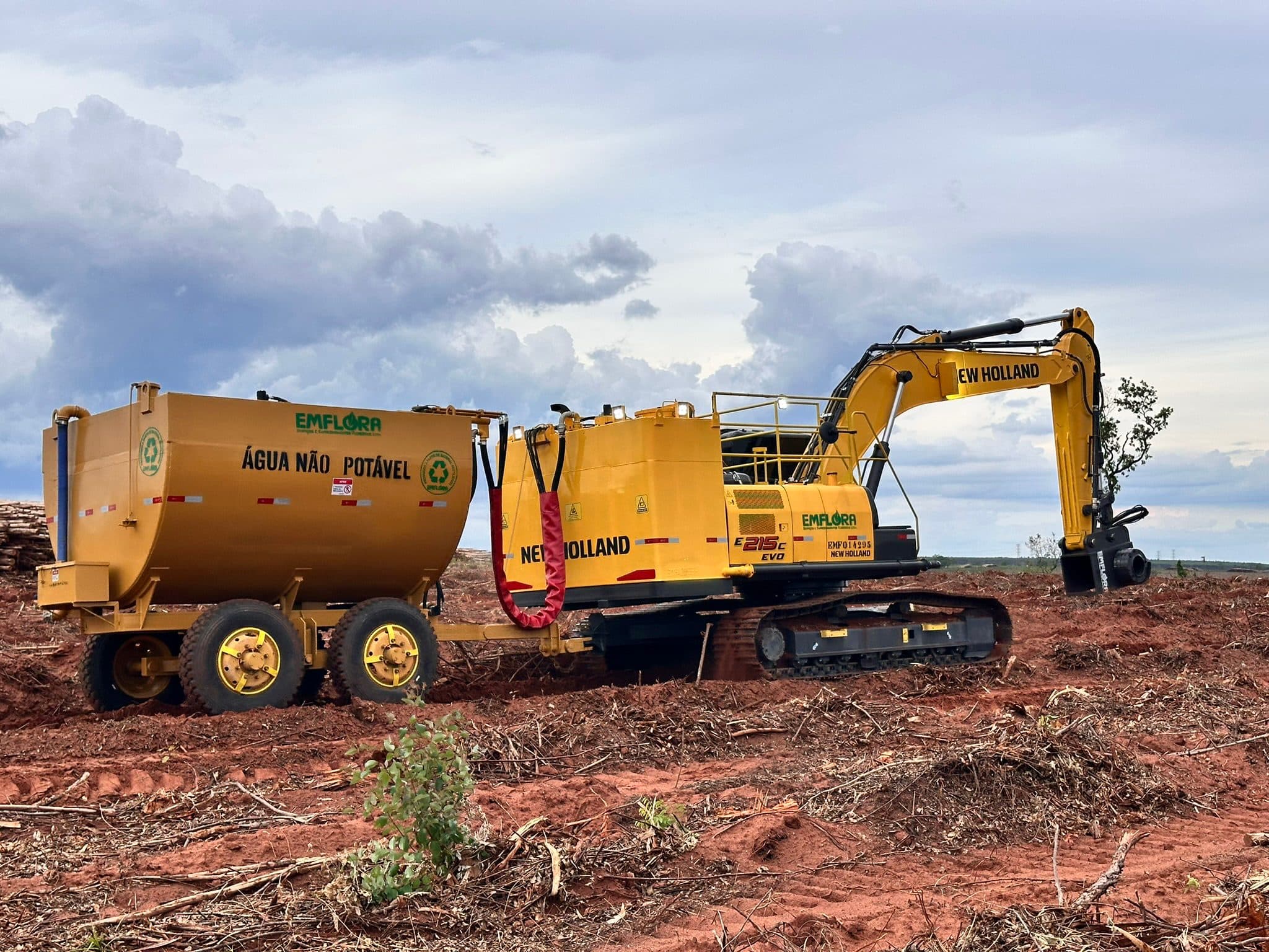 Escavadeira New Holland da Emflora puxando tanque de irrigação em campo florestal